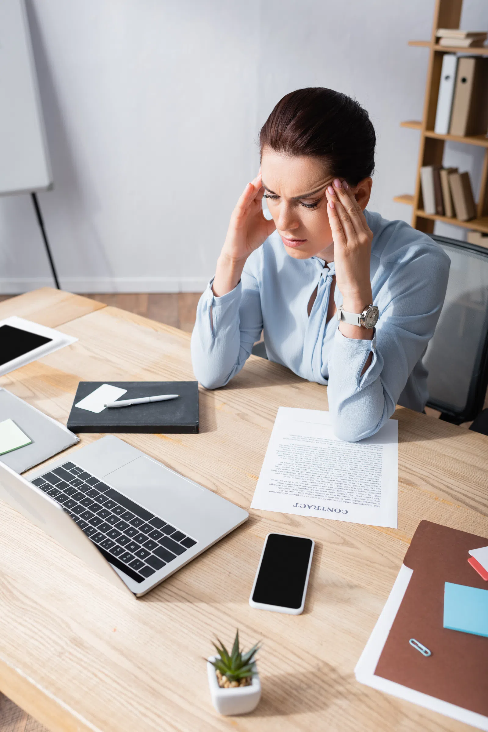 a person sitting at a desk with the hands on the face