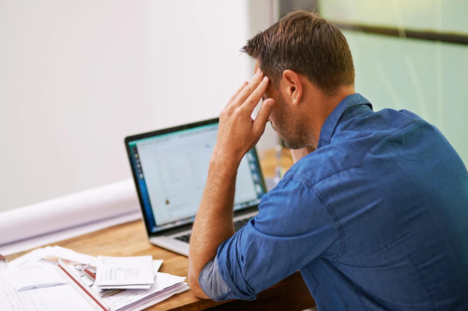 a man sitting at a desk with his hand on his face