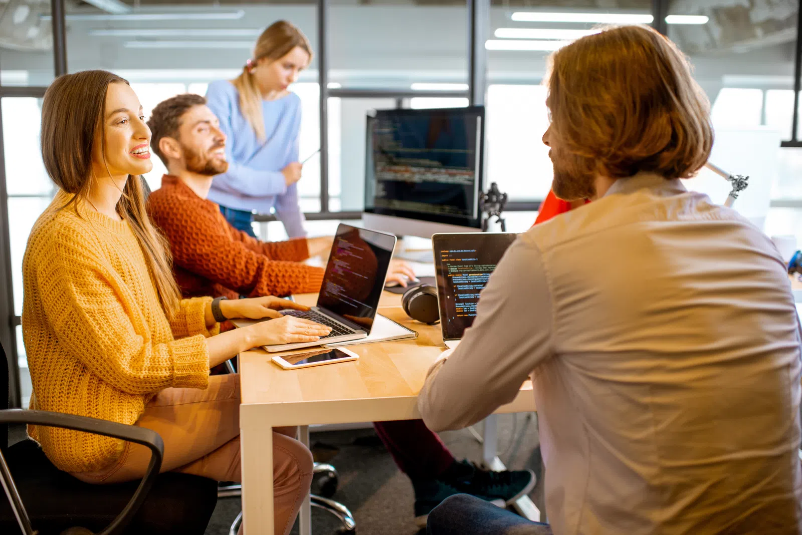 a group of people sitting at a table with laptops