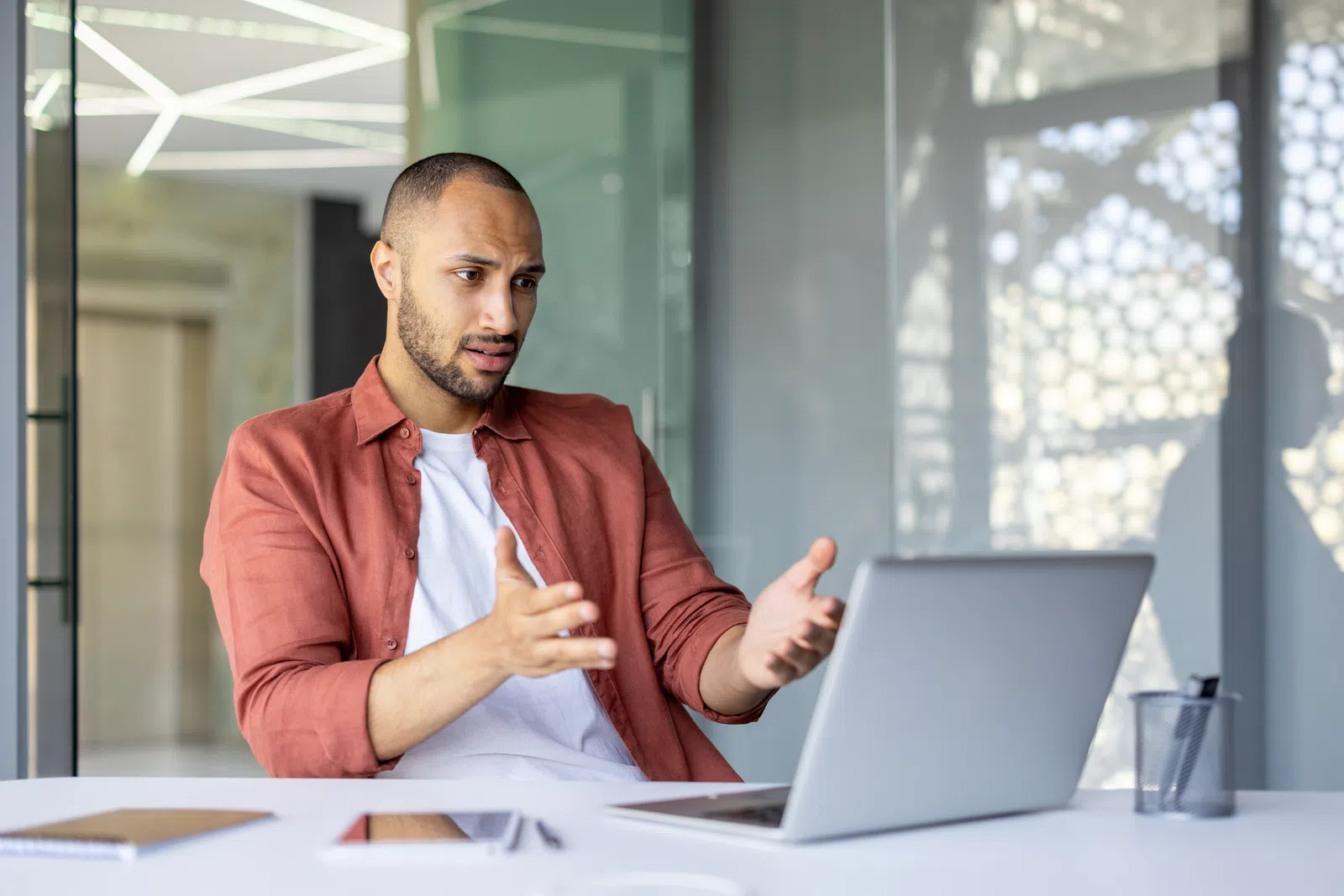 a man sitting at a table with a laptop and a window